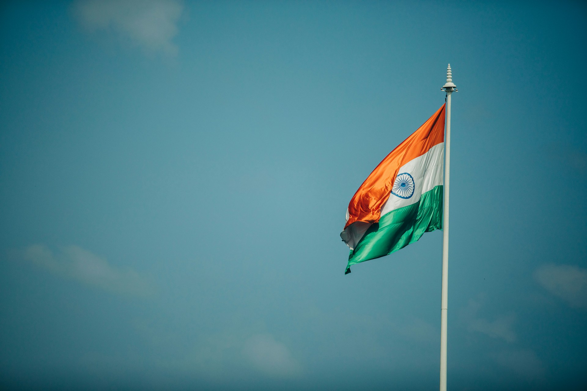 India Flag Hanging On A Flagpole With A Blue Sky