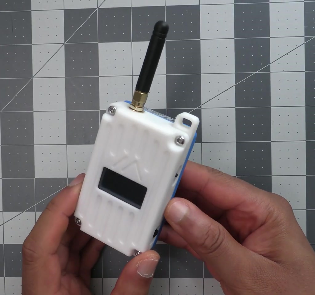 Hand holding a compact mesh radio device displaying a map and a chat interface