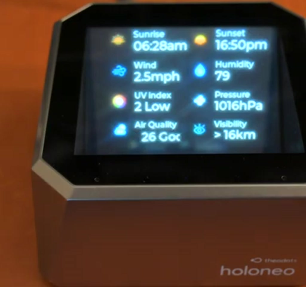 Vertical image of the Holo Neo puck projecting a translucent 3D interface above a minimalist desk with soft backlighting