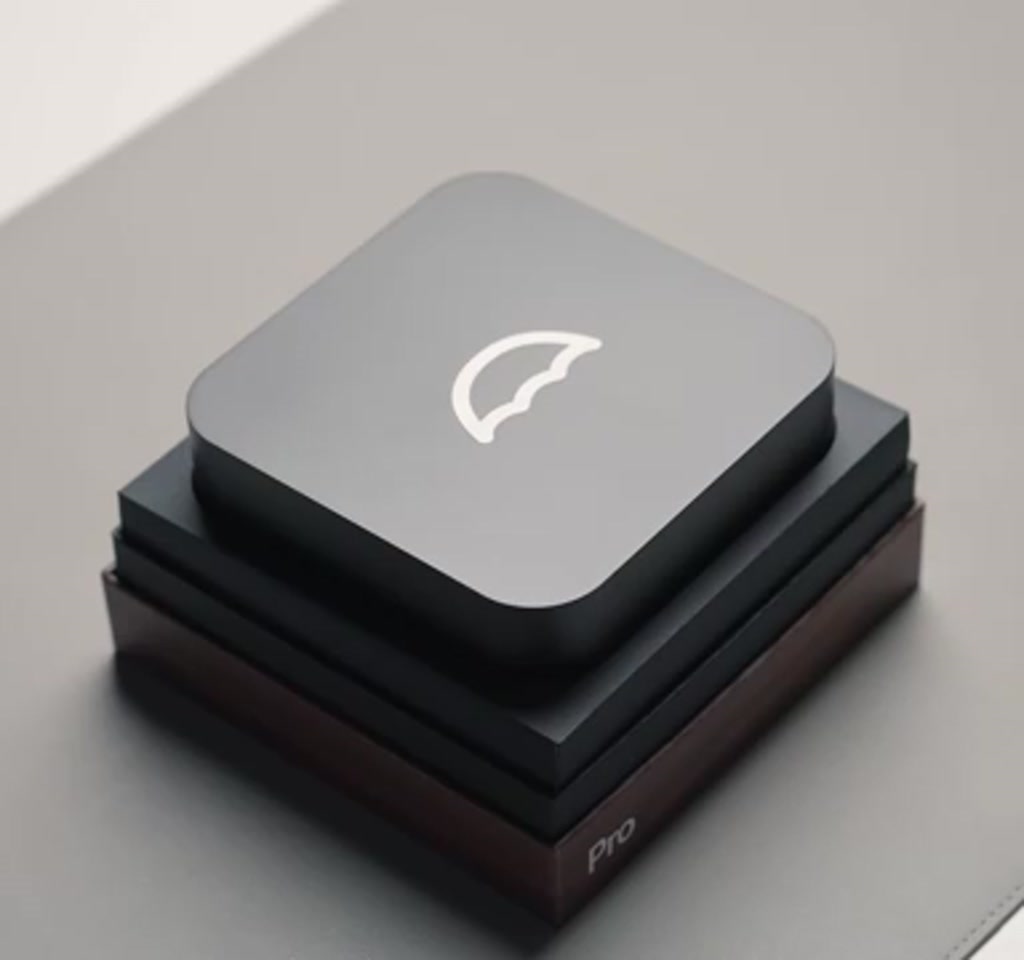 Vertical view of an Umbrel Pro home server on a shelf with network cables and a laptop showing a local cloud dashboard